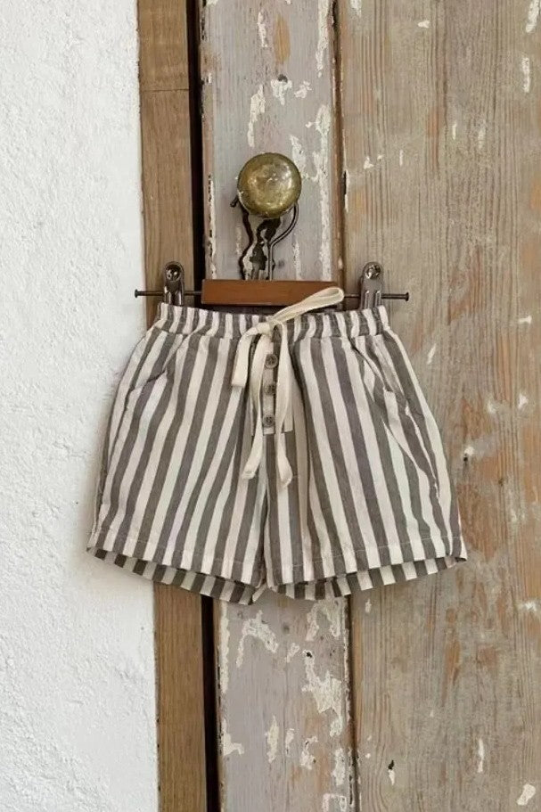 Striped shorts hanging on a wooden hook against a white wall.