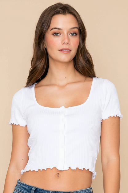 Woman wearing a white crop top and denim shorts on a plain background