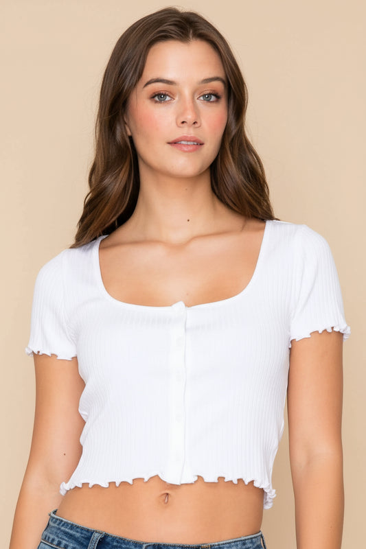 Woman wearing a white crop top and denim shorts on a plain background