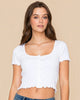Woman wearing a white crop top and denim shorts on a plain background