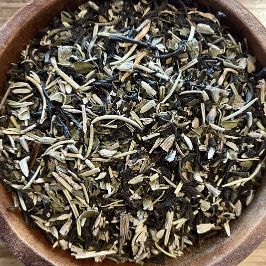 Dry tea leaves in a wooden bowl on a wooden surface