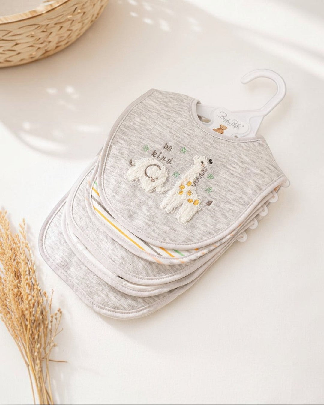 Stack of gray baby bibs with embroidered designs on a white surface