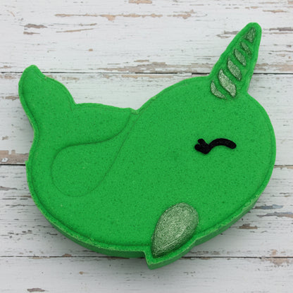 Green felt whale toy on pebbles