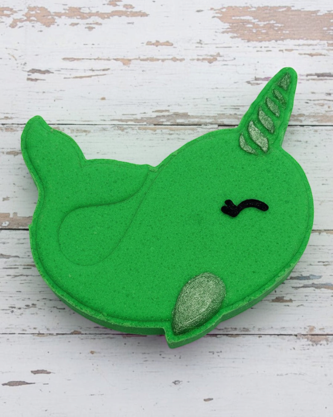 Green felt whale toy on pebbles
