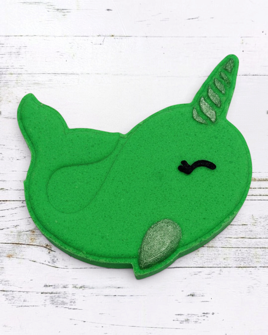 Green felt whale toy on pebbles