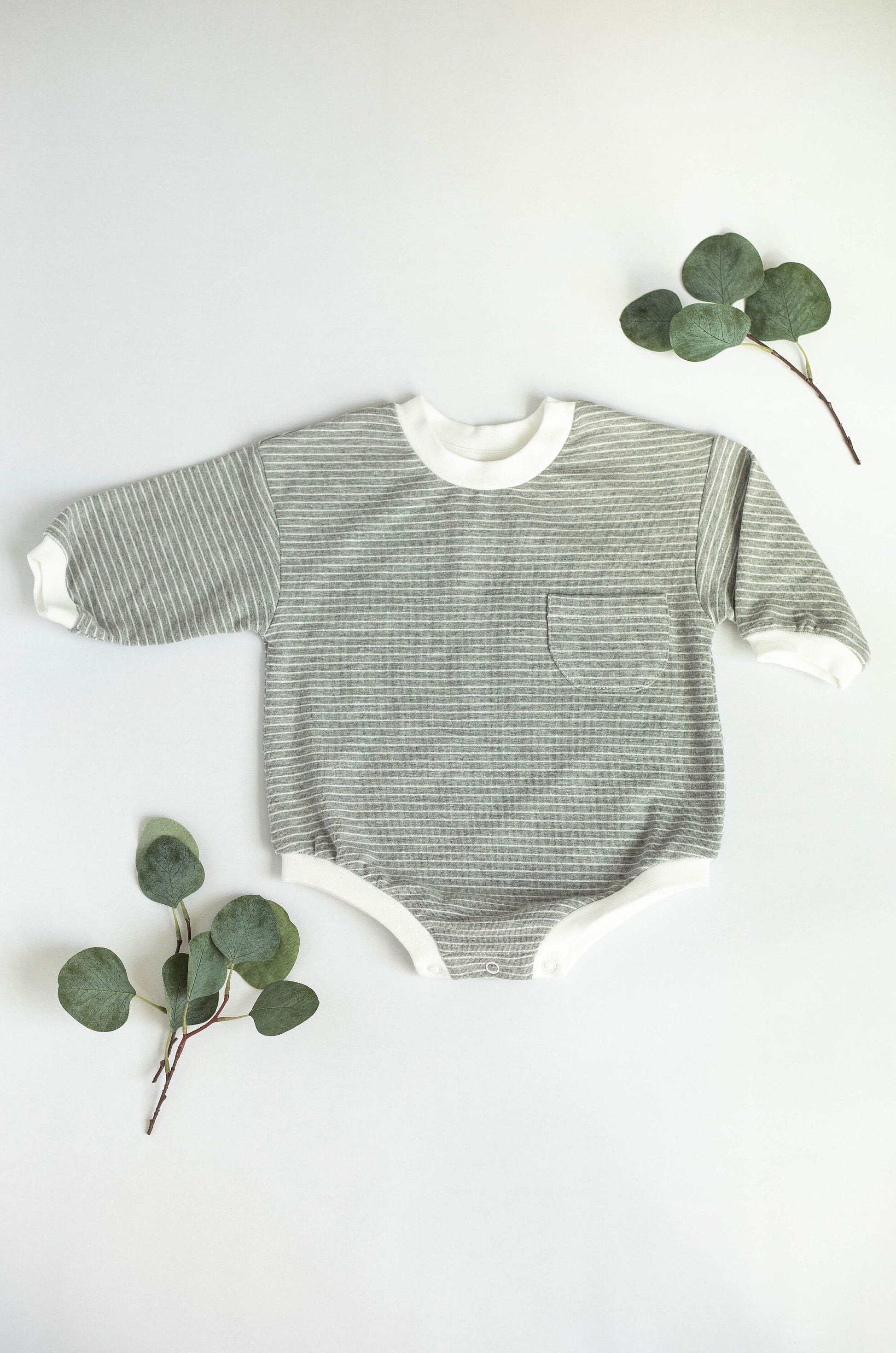 Striped baby onesie with eucalyptus leaves on a white background