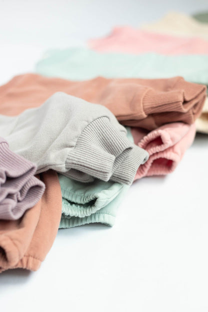 Stack of folded pastel-colored sweaters on a white surface