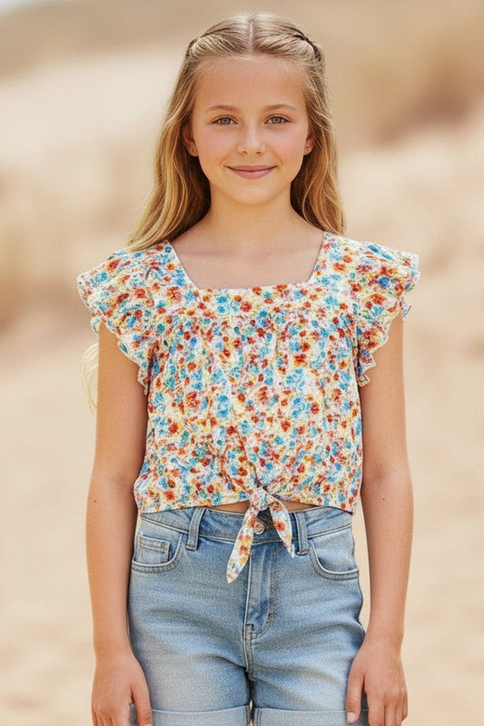 Young girl wearing a floral top and jeans against a beige background