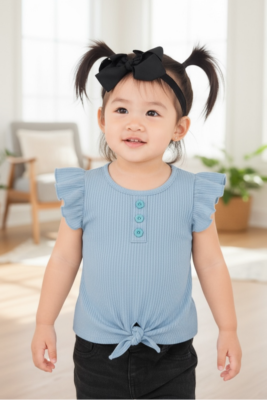 Child wearing a blue top with buttons in a bright room