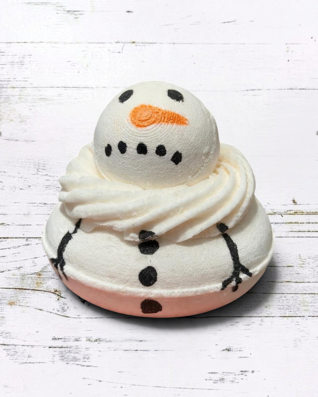 Calla Lily Cosmetics + CL kids hand-painted white snowman bath bomb with orange nose and black details in a hand