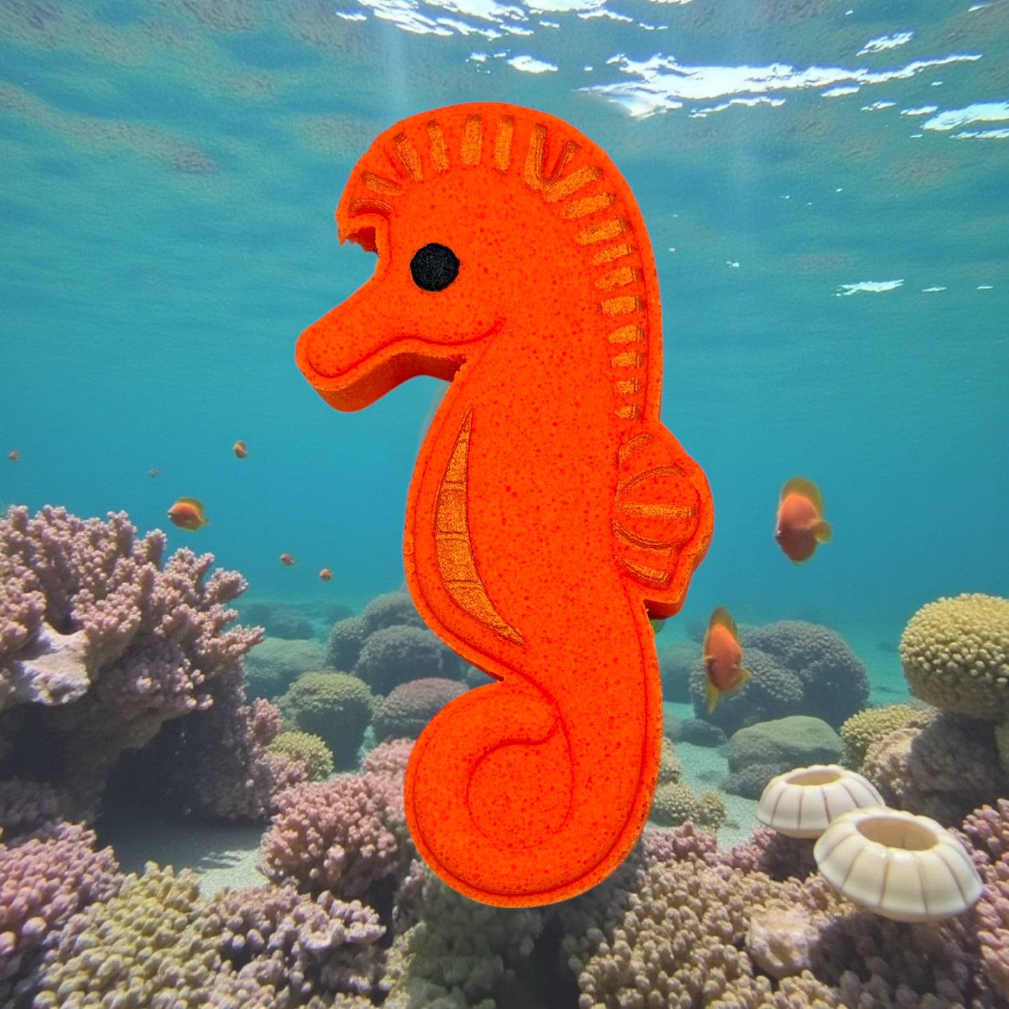 Orange seahorse-shaped toy floating in an underwater scene with coral and fish.