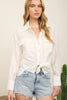 Woman wearing a white blouse and denim shorts with a cactus plant in the background