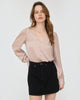 Woman wearing a beige blouse and black skirt on a white background