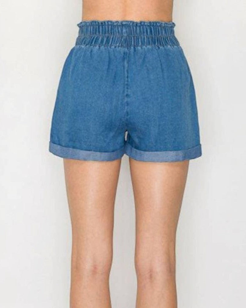 Blue denim shorts worn by a person on a white background
