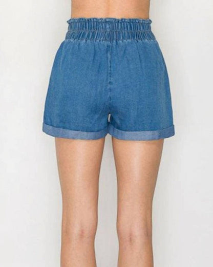Blue denim shorts worn by a person on a white background