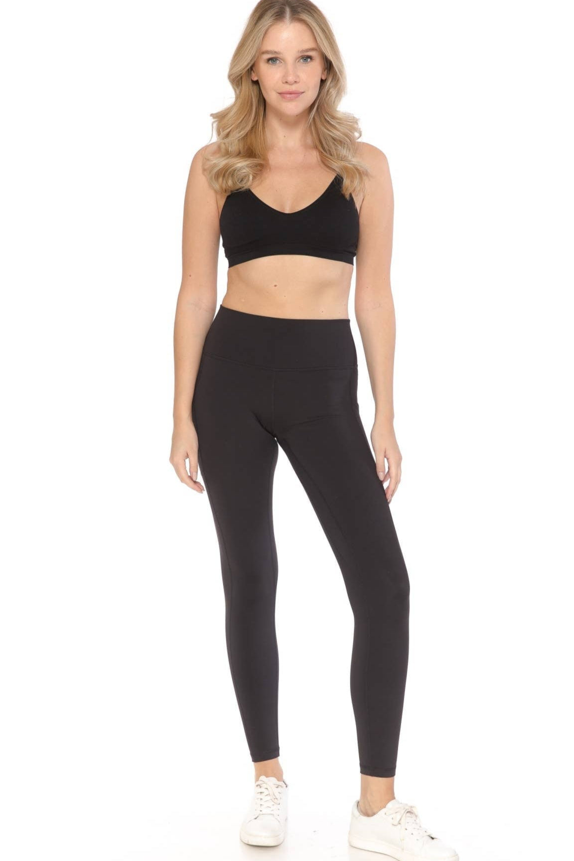 Woman wearing a black sports bra and leggings set on a white background