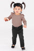 Child wearing a brown top and black pants on a white background
