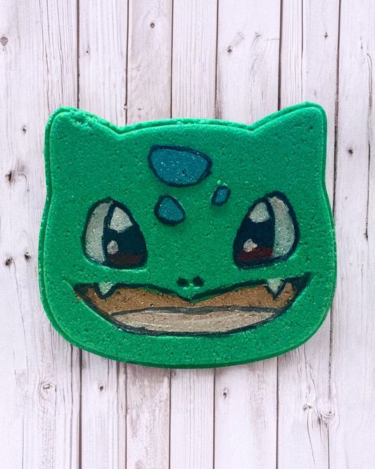 Calla Lily Cosmetics + CL kids Bulbasaur shaped green bath bomb with hand-painted details on a white wood background