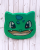 Calla Lily Cosmetics + CL kids Bulbasaur shaped green bath bomb with hand-painted details on a white wood background
