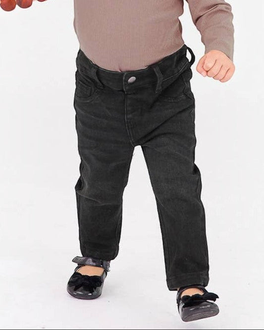 Child wearing a brown top and black pants on a white background