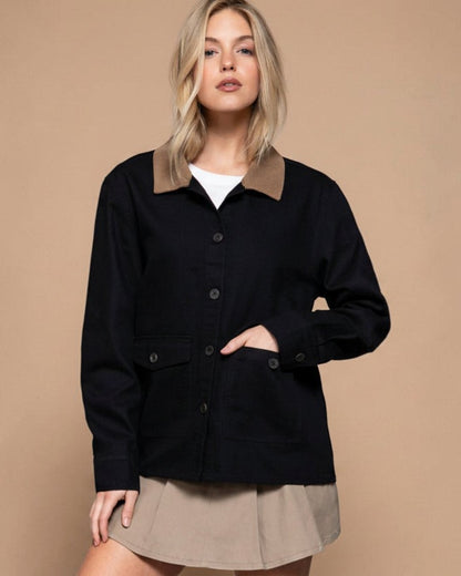 Woman wearing a black jacket with a beige collar against a gray background