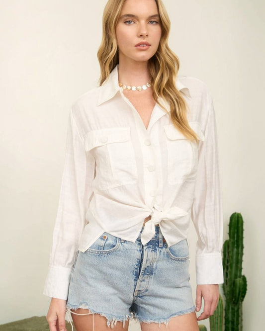 Woman wearing a white blouse and denim shorts with a cactus plant in the background