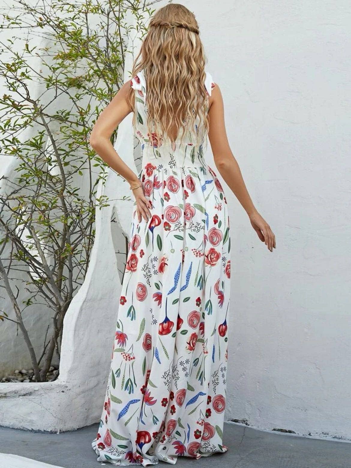 Woman wearing a floral dress against a white wall.