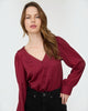 Woman wearing a burgundy blouse against a white background