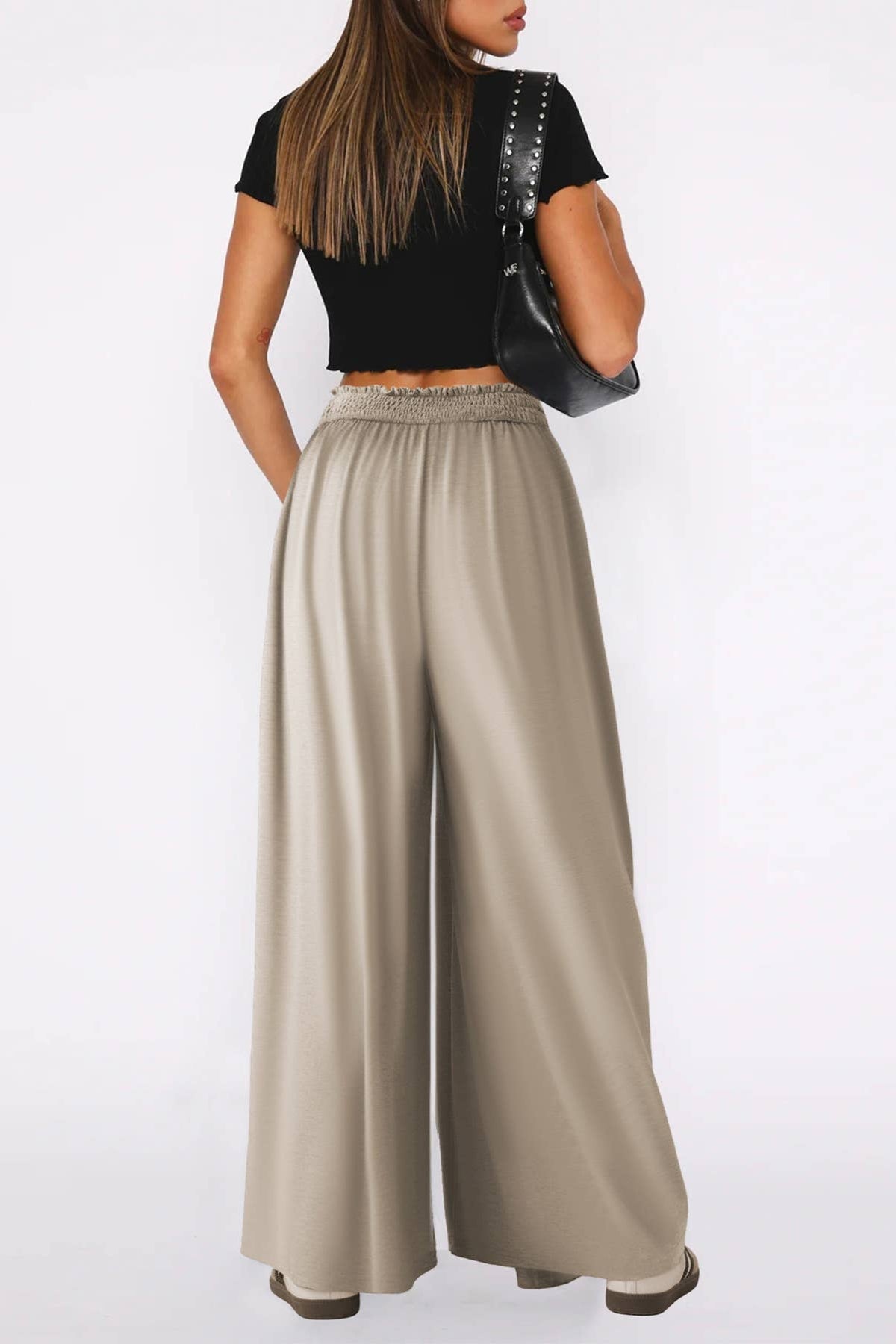 Woman wearing a black top and beige wide-leg pants on a white background