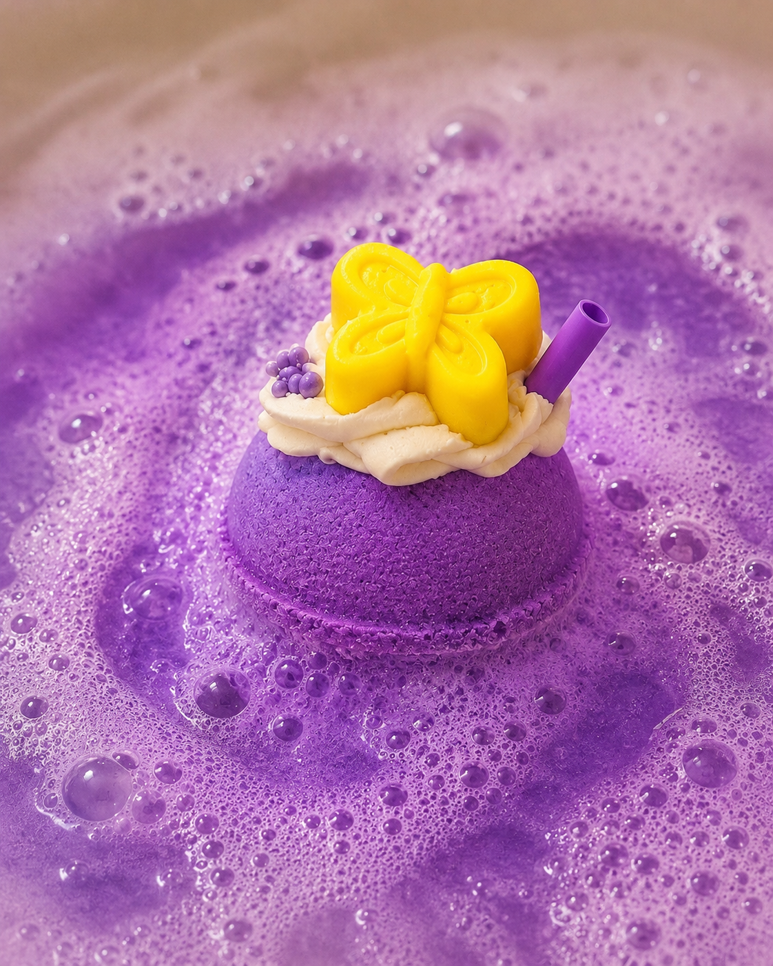 Purple bath bomb with a yellow butterfly on top, surrounded by bubbles.