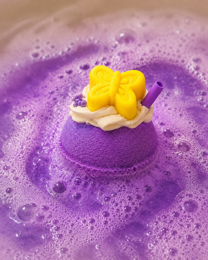Purple bath bomb with a yellow butterfly on top, surrounded by bubbles.