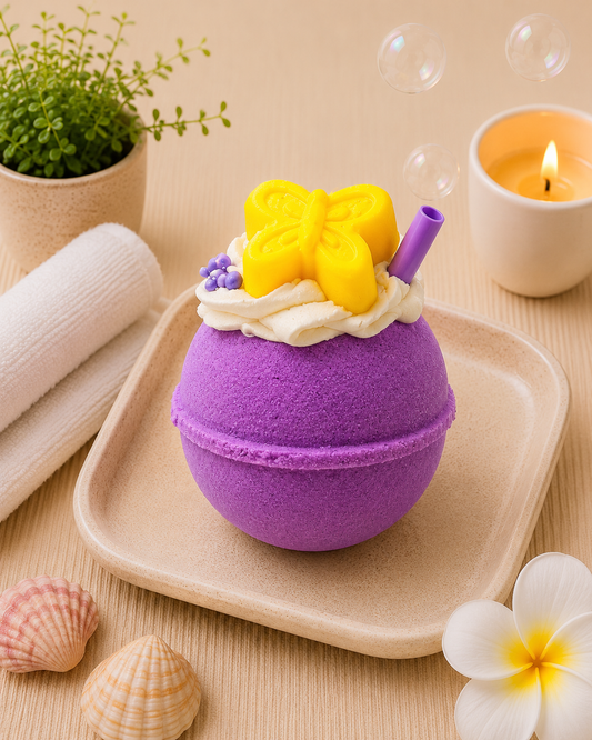 Purple bath bomb with yellow flowers and white foam on a beige tray, surrounded by bubbles, shells, and a candle.