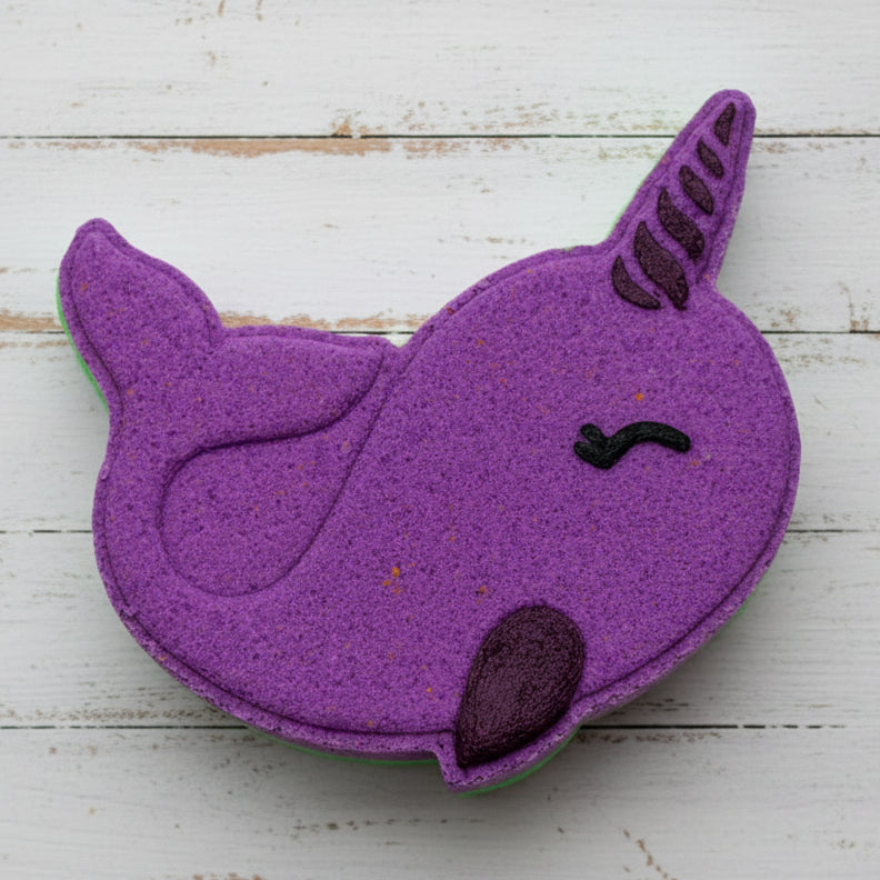 Purple cat-shaped bath bomb on a bed of multicolored stones