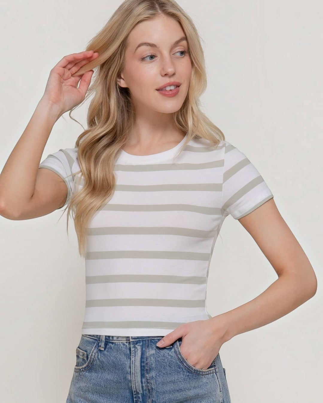 Woman wearing a striped shirt and jeans against a plain background
