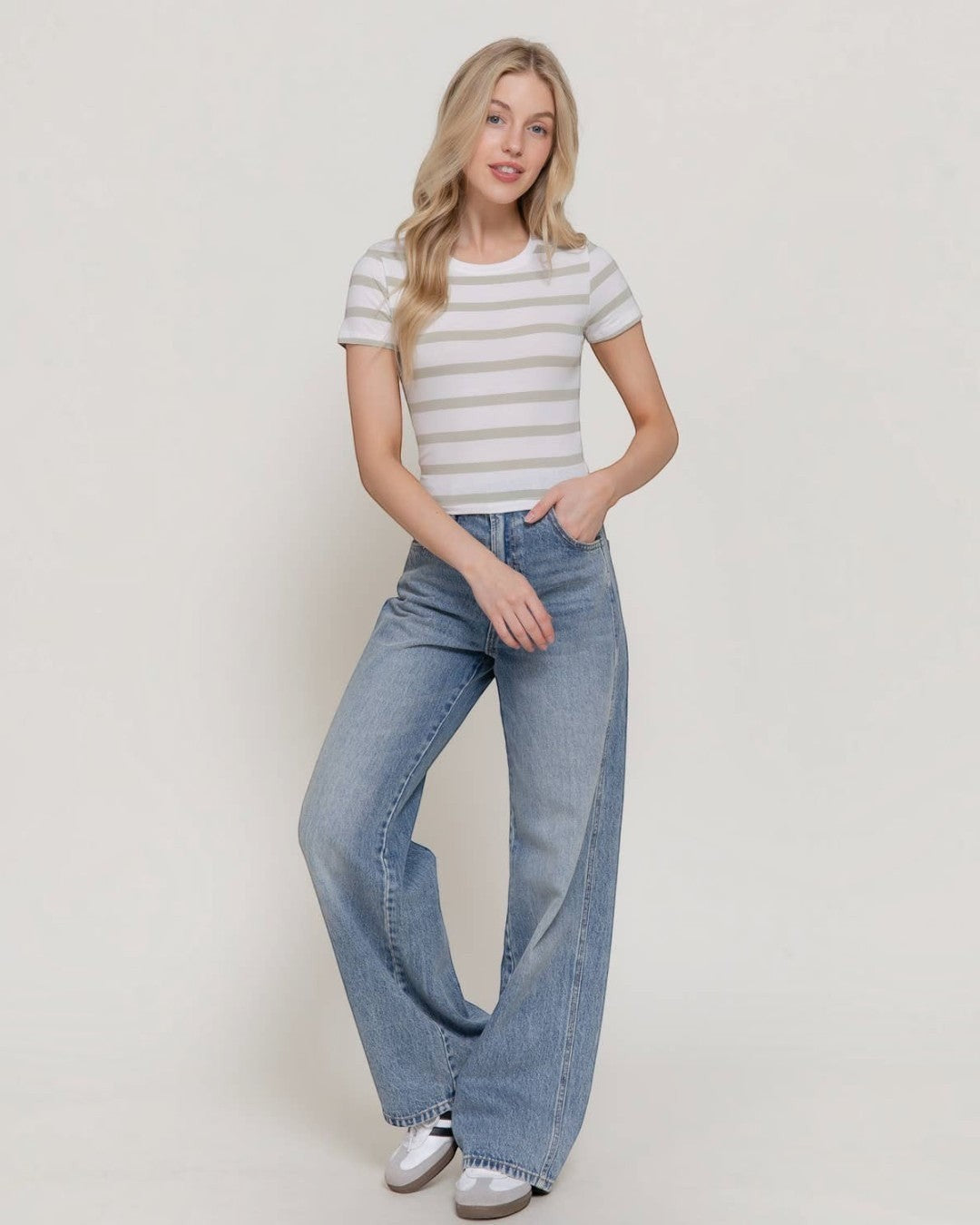 Woman wearing a striped shirt and wide-leg jeans against a plain background