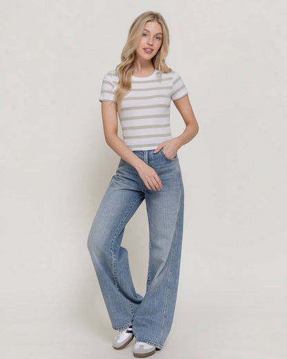 Woman wearing a striped shirt and wide-leg jeans against a plain background