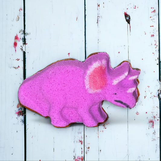 Pink dinosaur-shaped cookie on a white wooden surface