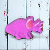 Pink dinosaur-shaped cookie on a white wooden surface
