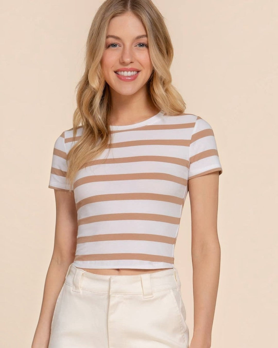 Woman wearing a striped shirt and white pants on a beige background