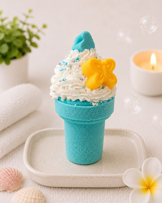 Blue bath bomb with white foam and yellow butterfly on a white surface with a candle and plant in the background.