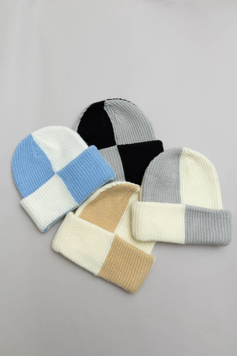 Four patchwork-style beanies in different color combinations on a gray background