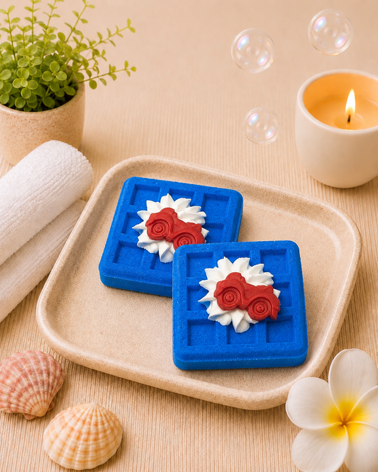 Two blue square coasters with floral designs on a beige tray, surrounded by bubbles, a candle, and shells.