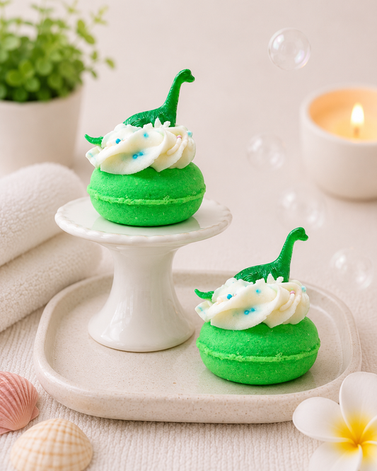 Green macarons with white frosting and green hats on a white plate with a candle and plant in the background.