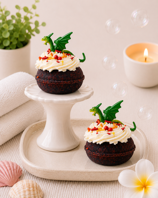 Two decorated cupcakes on a white stand with a candle and flowers in the background.