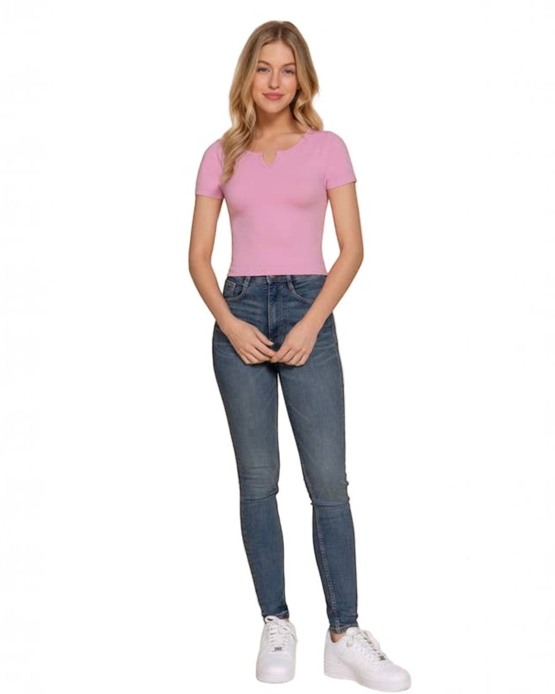 Woman wearing a pink top and blue jeans on a beige background