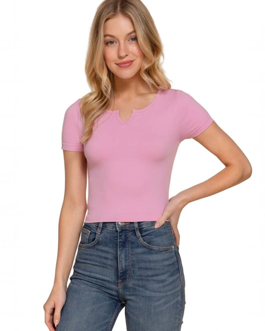 Woman wearing a pink top and blue jeans on a beige background