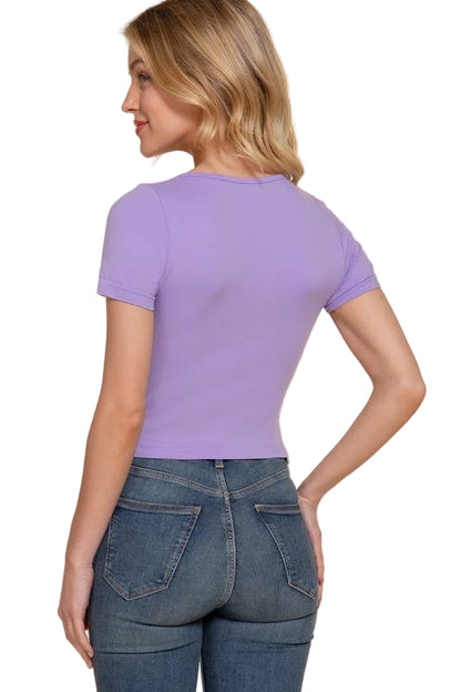 Woman wearing a purple t-shirt and blue jeans on a beige background