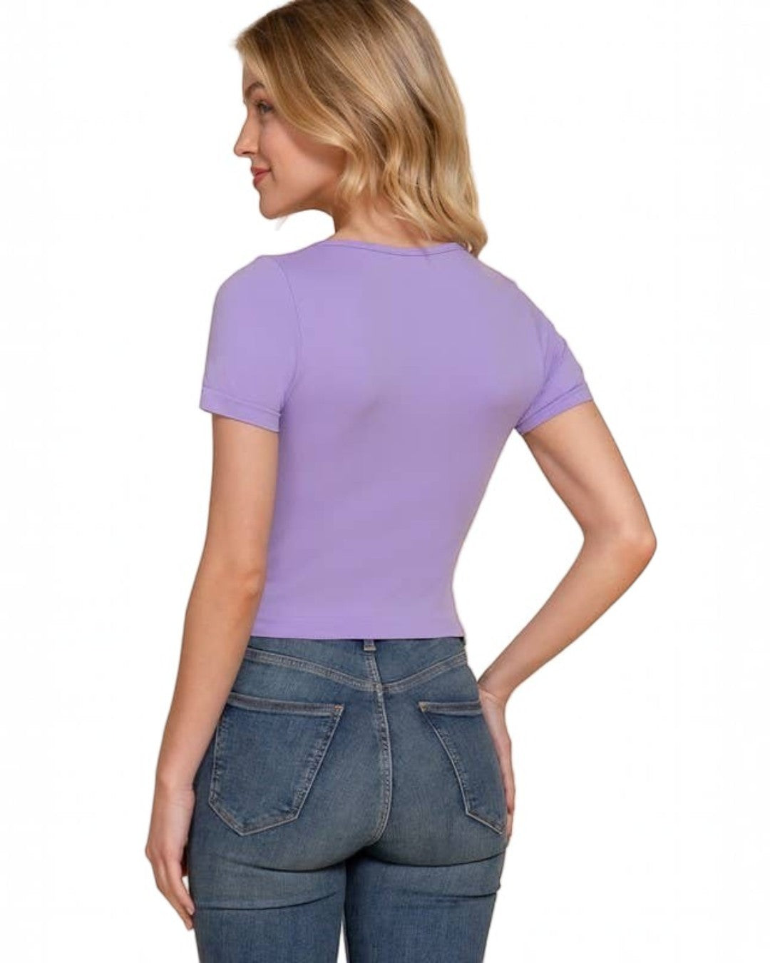 Woman wearing a purple t-shirt and blue jeans on a beige background