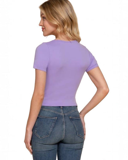 Woman wearing a purple t-shirt and blue jeans on a beige background