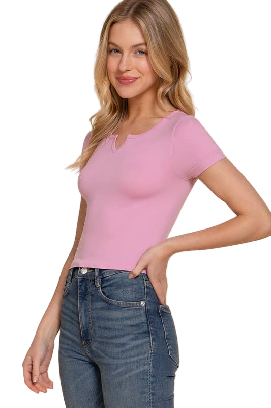 Woman wearing a pink top and blue jeans on a beige background